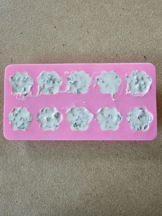 Paw shaped silicone mold filled with the fresh breath dog treat mixture.