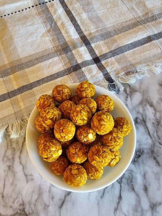 Ball shaped no bake dog treats in a white bowl next to a linen towel.
