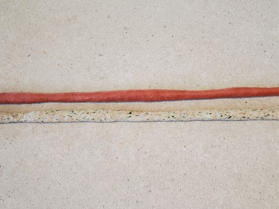 Red dough and spinach flecked dough rolled out into two long strands.
