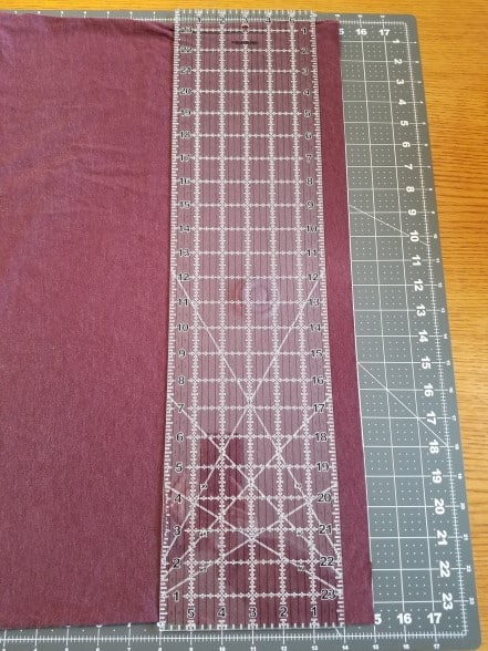 A t-shirt laid on a cutting mat with acrylic ruler set to cut at 1 inch.