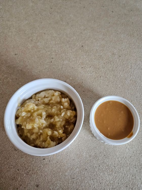 Mashed banana and peanut butter in separate white bowls on a counter.