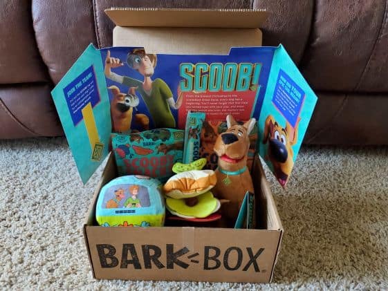 A Scooby Doo themed bark box with a scooby doo plush toy, mystery machine plush toy, and sandwich plush toy along with 2 bags of treats and chew treat.