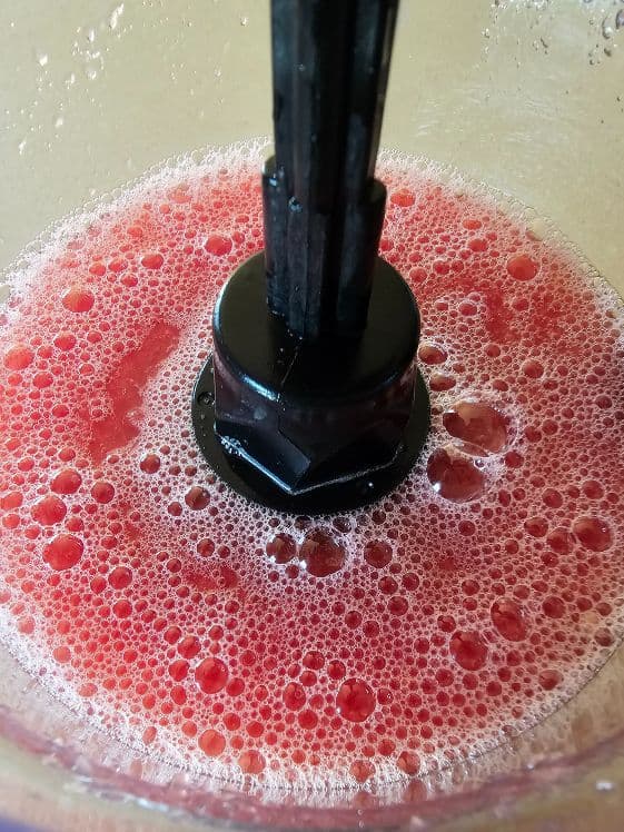 A food processor with pureed watermelon in it.