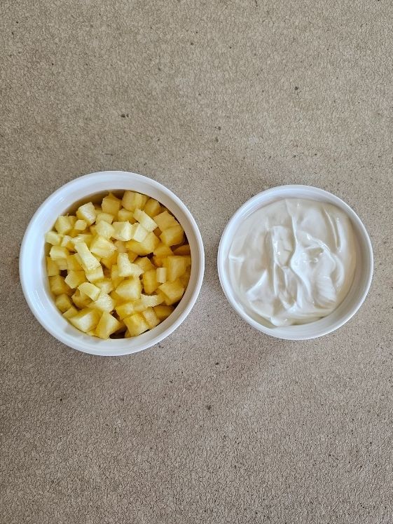 Chopped pineapple and Greek yogurt in individual white bowls.