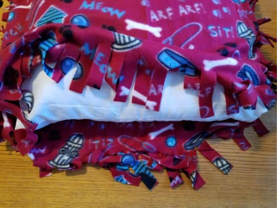 The pillow between the top and bottom pieces of fleece after three sides are tied together.