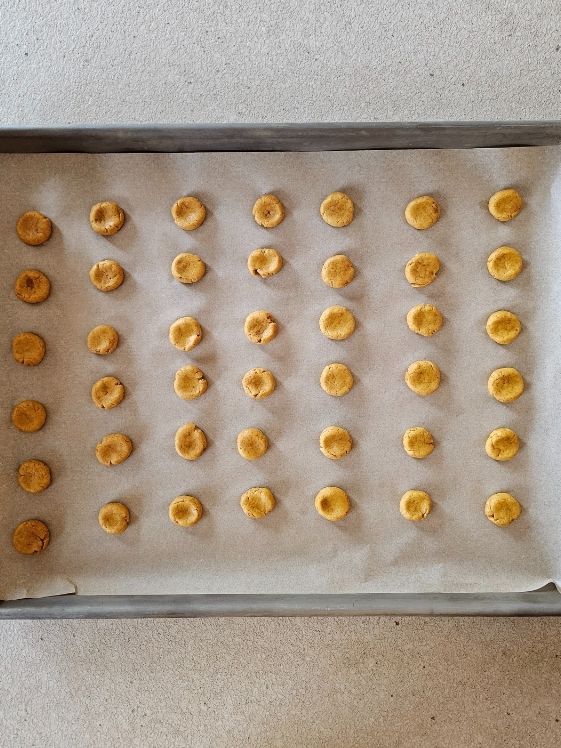 The dough in small circles on a cookie sheet lined with parchment paper.