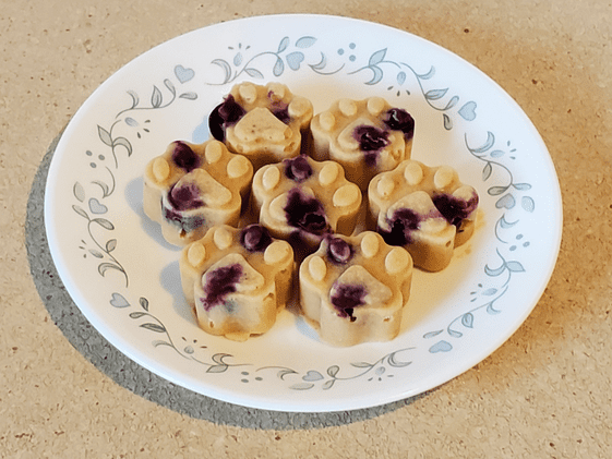 Paw shaped frozen applesauce dog treats on a plate.