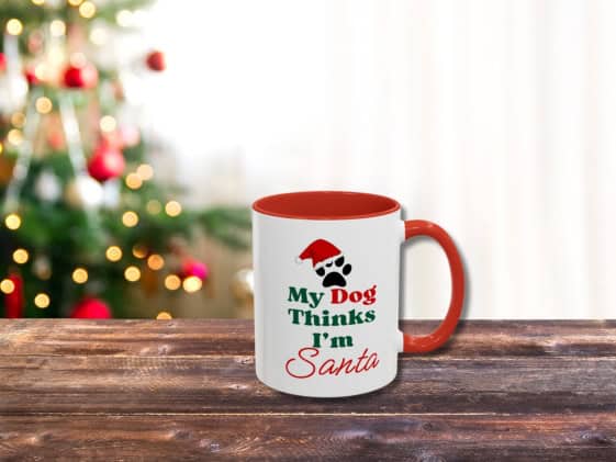 A white mug with red handle and the text "My dog thinks I'm Santa" on it.