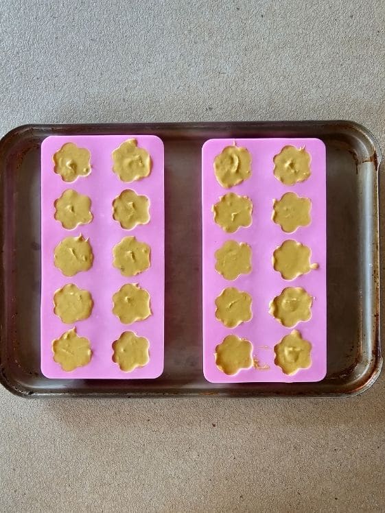 Paw shaped molds filled with peanut butter pumpkin mixture.