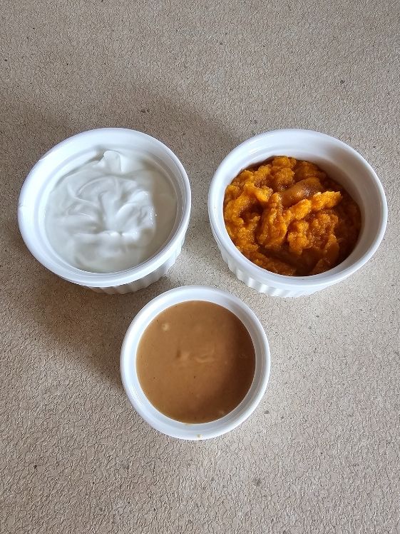 Greek yogurt, pumpkin puree, and peanut butter in individual white bowls.