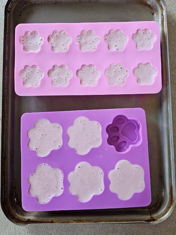Paw shaped molds filled with strawberry yogurt mixture.