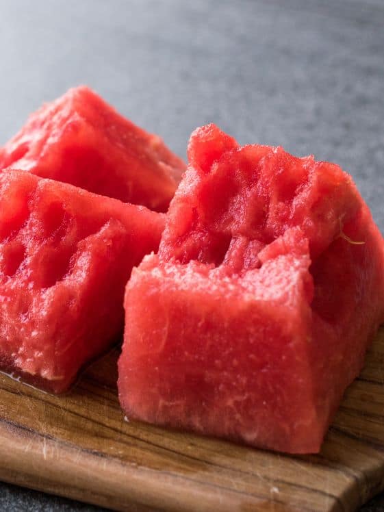 Cut pieces of watermelon without the seeds on a cutting board.