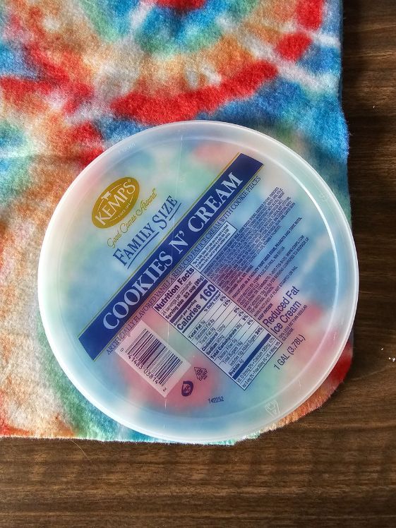 An ice cream pail lid on top of fleece that is laid out on a table.