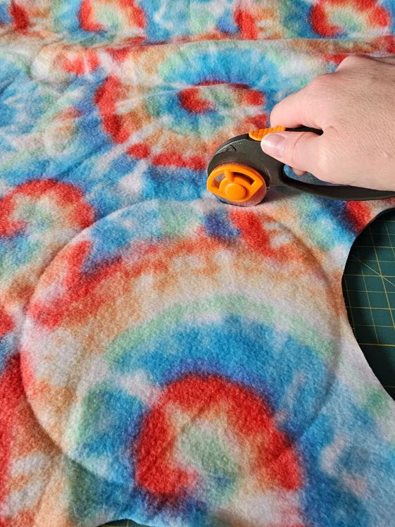 Cutting a circle out of fleece with a rotary cutter.