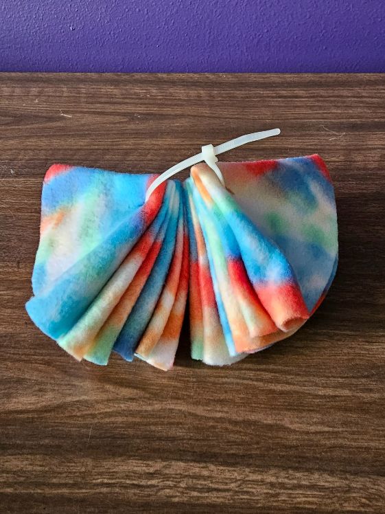 A zip tie with 8 folded fleece circles on it closed loosely.