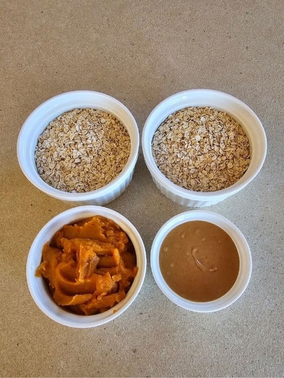 Quick oats, pumpkin puree, and peanut butter in individual white bowls.