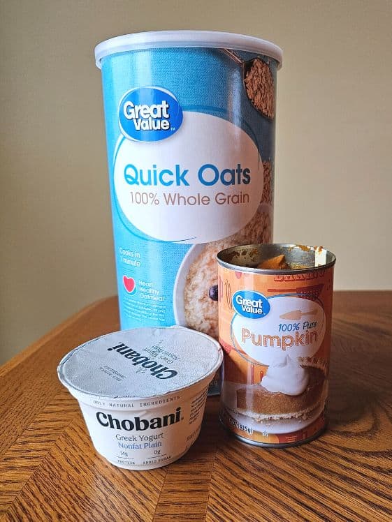 An individual size Greek yogurt, a can of pumpkin puree, and a container of quick oats.
