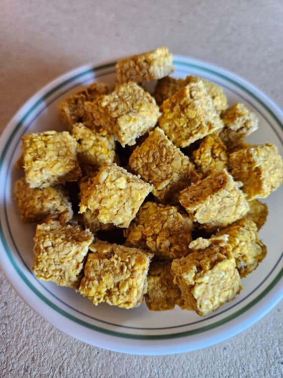 Apple pumpkin dog treats cut into squares and placed in a bowl.