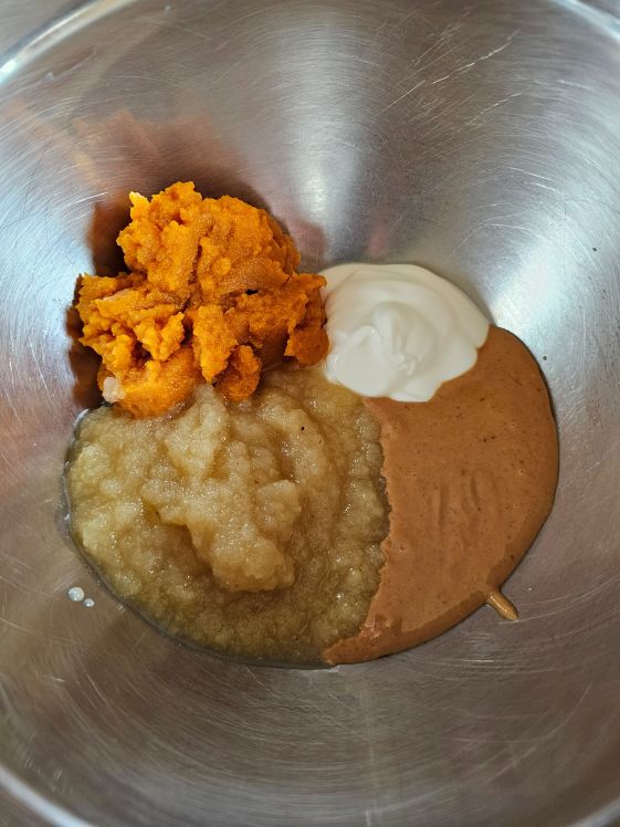 Pumpkin puree, plain Greek yogurt, creamy peanut butter, and applesauce in a mixing bowl.