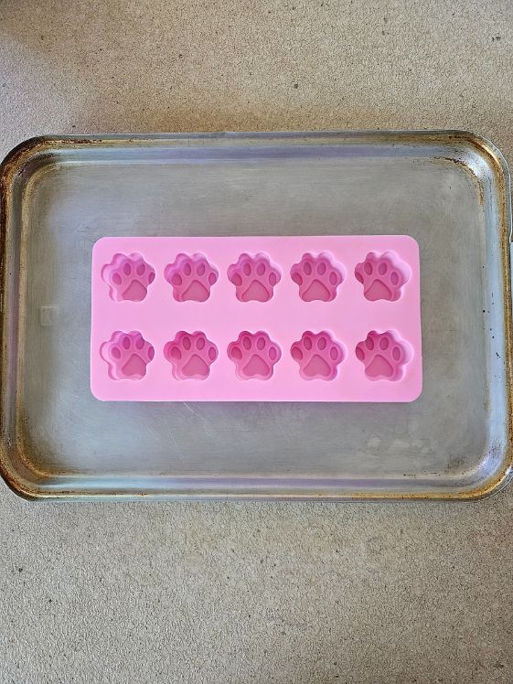 A paw shaped silicone mold on a cookie sheet.
