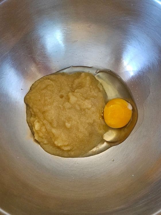 Applesauce and an egg in a mixing bowl.