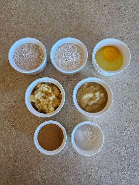 Ingredients for banana dog muffins in individual white bowls.