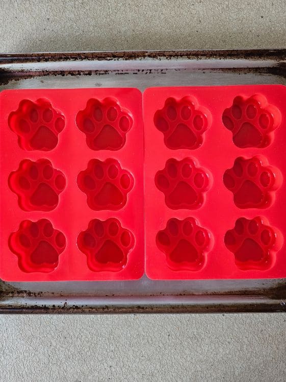 Paw shaped silicone molds on a cookie sheet.