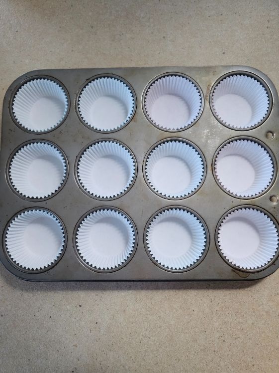 Muffin tin with cupcake liners in each spot.