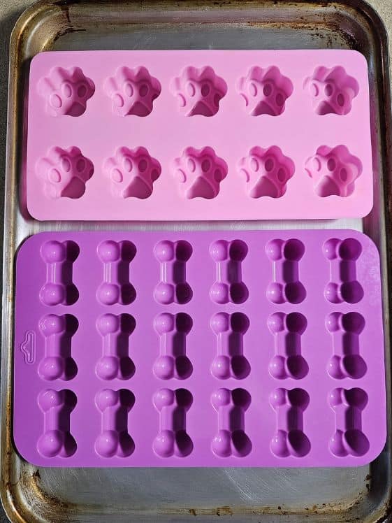 Paw and bone shaped silicone molds on a baking sheet.