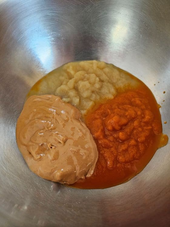 Peanut butter, applesauce, and carrot puree in a mixing bowl.
