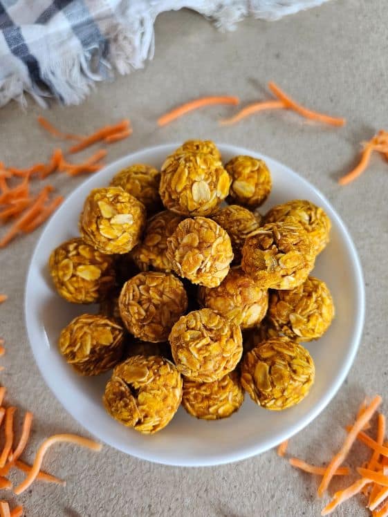Peanut butter carrot dog treats in a bowl with shredded carrots around it.