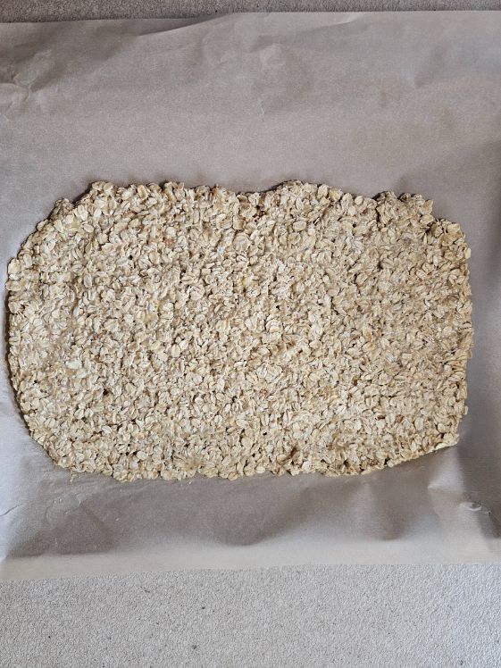Apple banana oats mixture pressed out onto a parchment paper lined baking sheet.