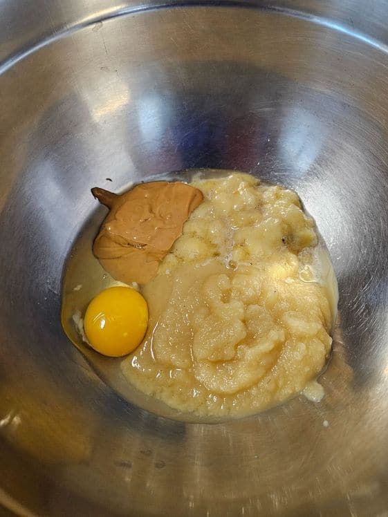 Egg, peanut butter, mashed banana, and applesauce in a mixing bowl.