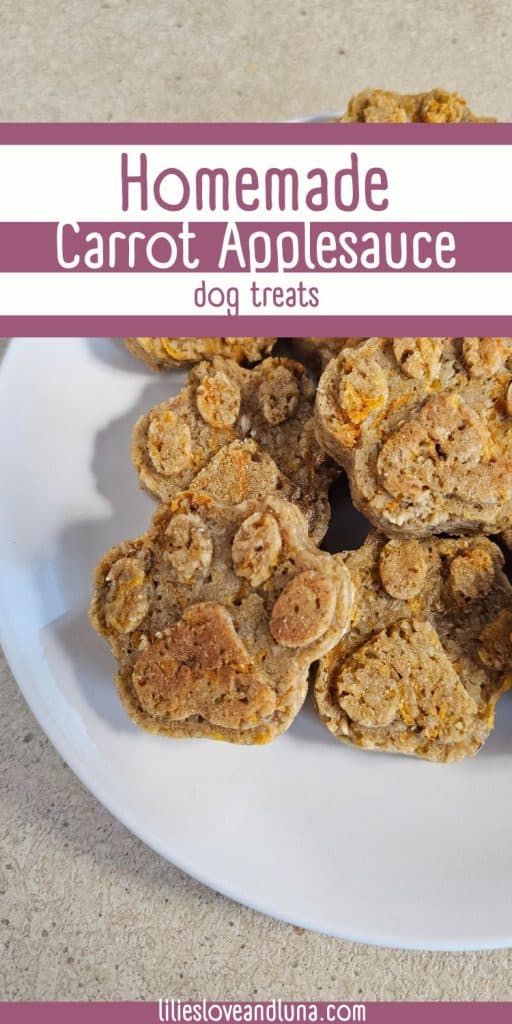 A plate of homemade dog treats shaped like paw prints, made with carrots and applesauce, sits on a countertop. A text overlay reads homemade carrot applesauce dog treats.