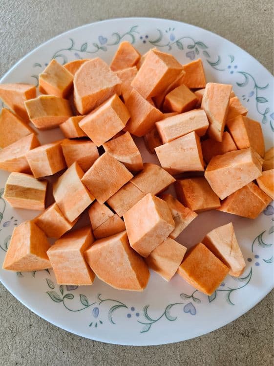 Peeled and chopped sweet potatoes on a plate.
