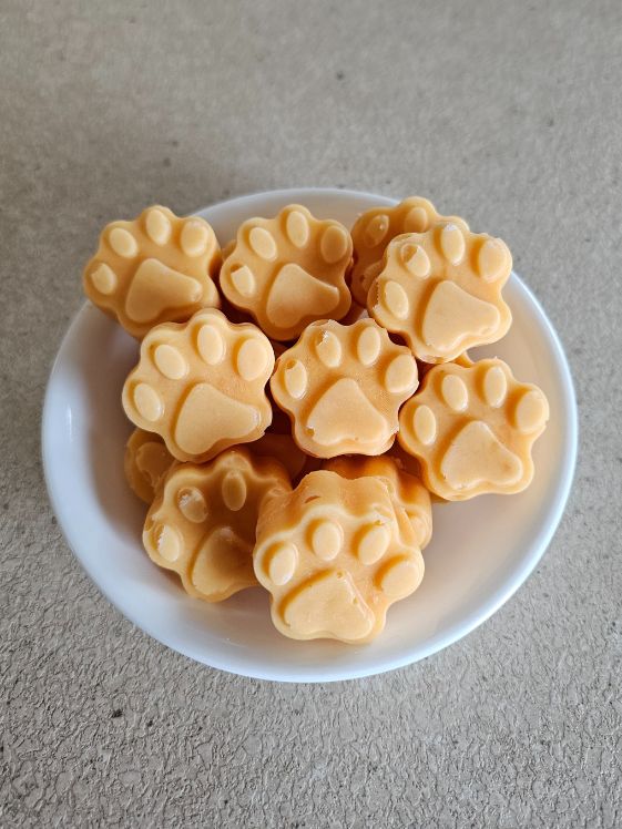 A bowl of sweet potato ice cream for dogs in a paw shape.
