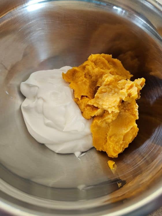 Greek yogurt and sweet potato puree in a mixing bowl.