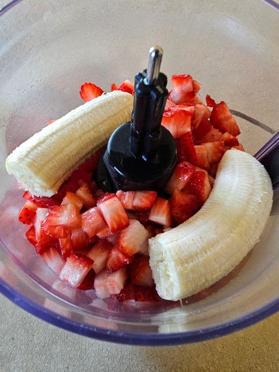 Watermelon, strawberries, and banana in a food processor.