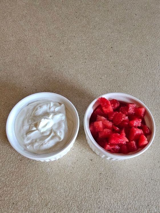 Plain Greek yogurt and chopped watermelon in individual white bowls.