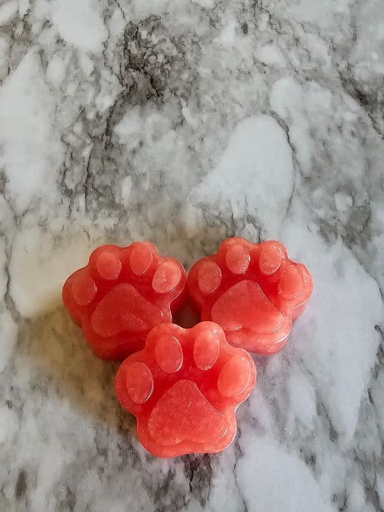 Three paw shaped easy watermelon dog treats on a marble surface.