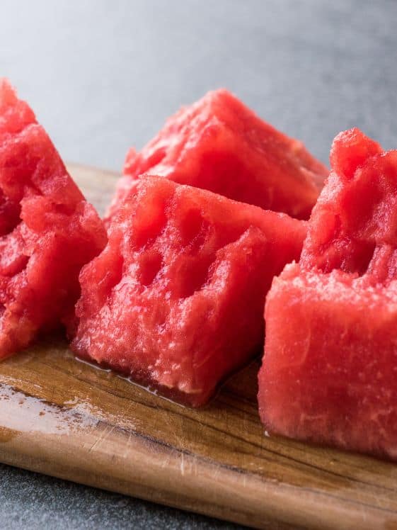 Pieces of watermelon on a wood cutting board.