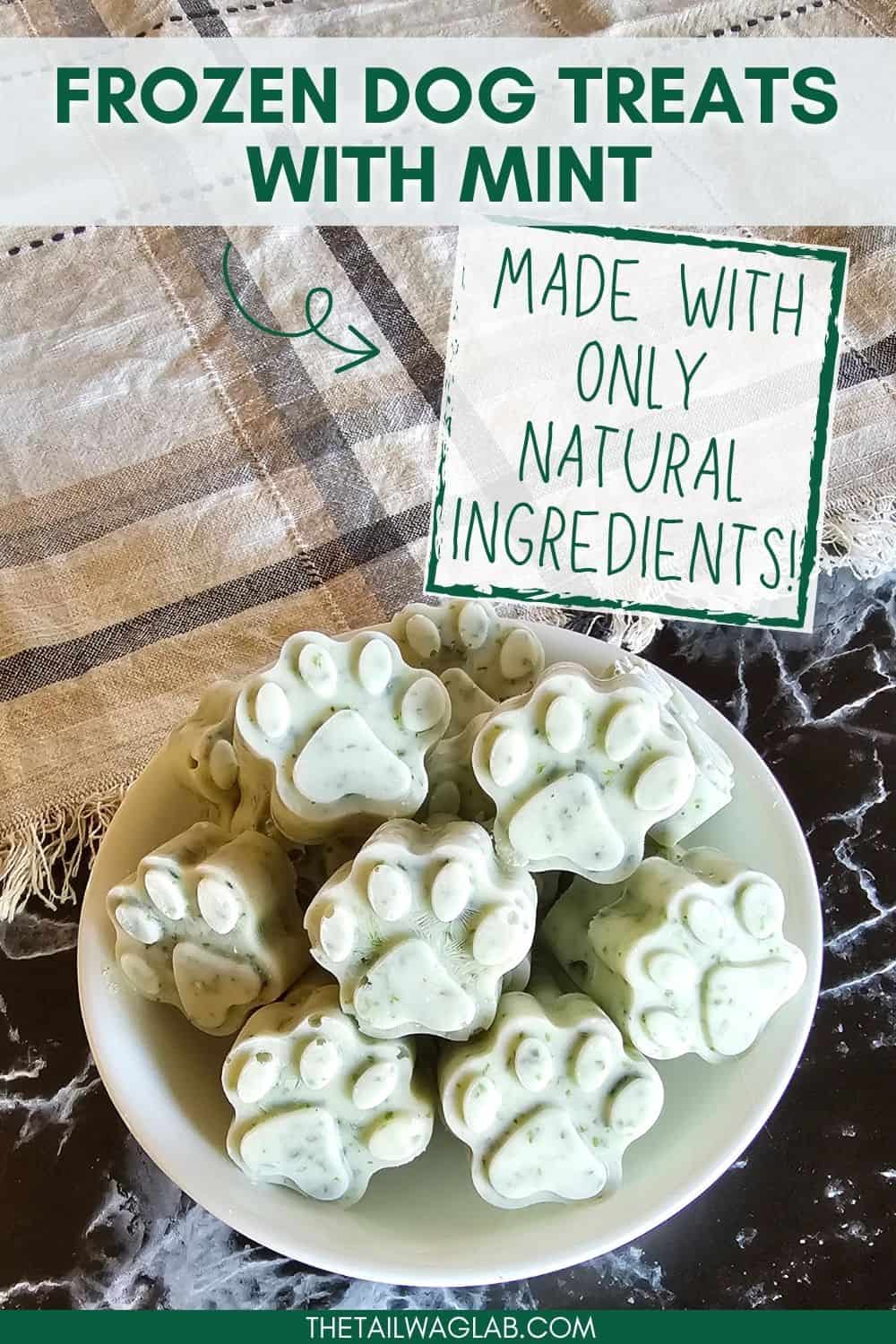 A bowl of frozen homemade dog treats in the shape of paw prints, made with natural ingredients including mint, displayed on a textured surface.