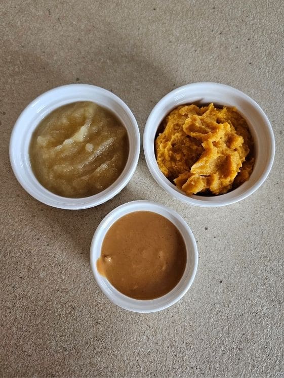Applesauce, sweet potato puree, and peanut butter in individual white bowls.
