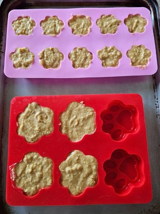 Paw shaped silicone molds filled with treat mixture ready for the freezer.