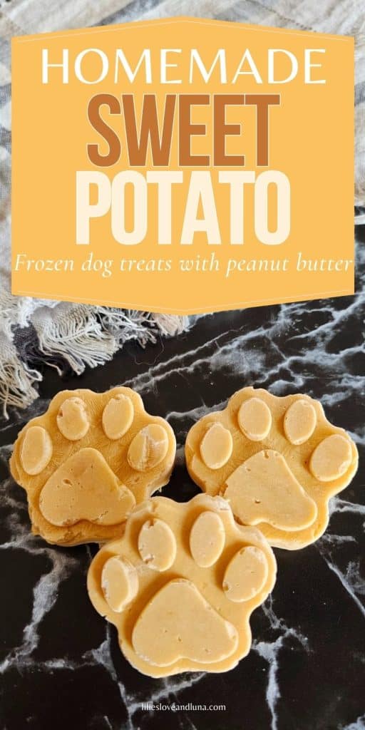 Three frozen paw-shaped dog treats made with sweet potato and peanut butter are arranged on a dark surface, promoting a homemade treat recipe.