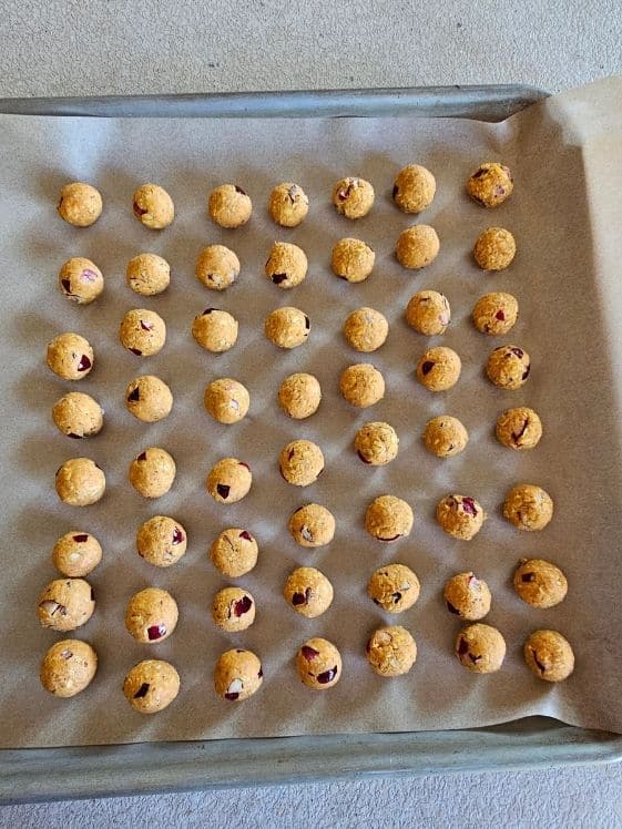 Cranberry oat balls on a parchment paper lined cookie sheet.