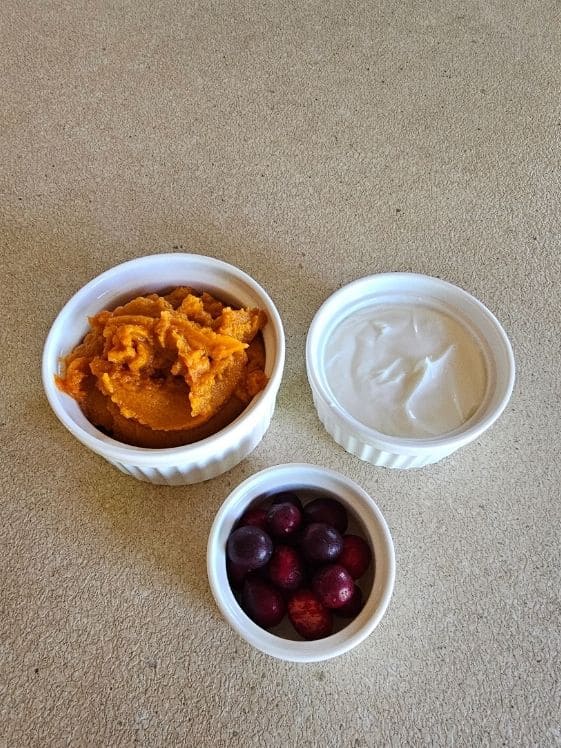 Pumpkin puree, Greek yogurt, and whole cranberries in individual white bowls.