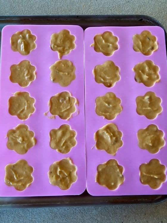 Paw shaped silicone molds filled with dog treat mixture.