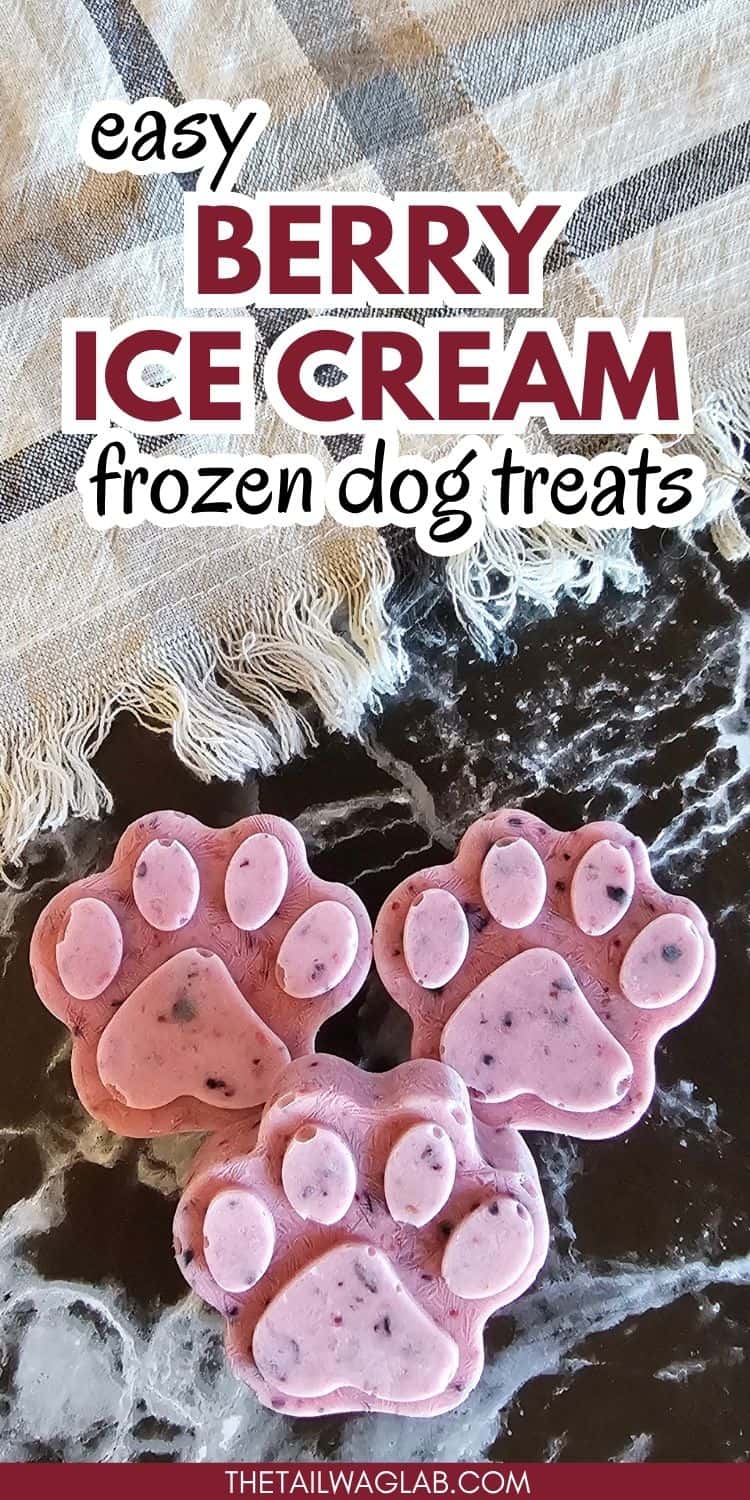 Three paw-shaped frozen dog treats in shades of pink are displayed on a dark surface, alongside a textured cloth, suggesting a recipe for easy berry ice cream dog treats.