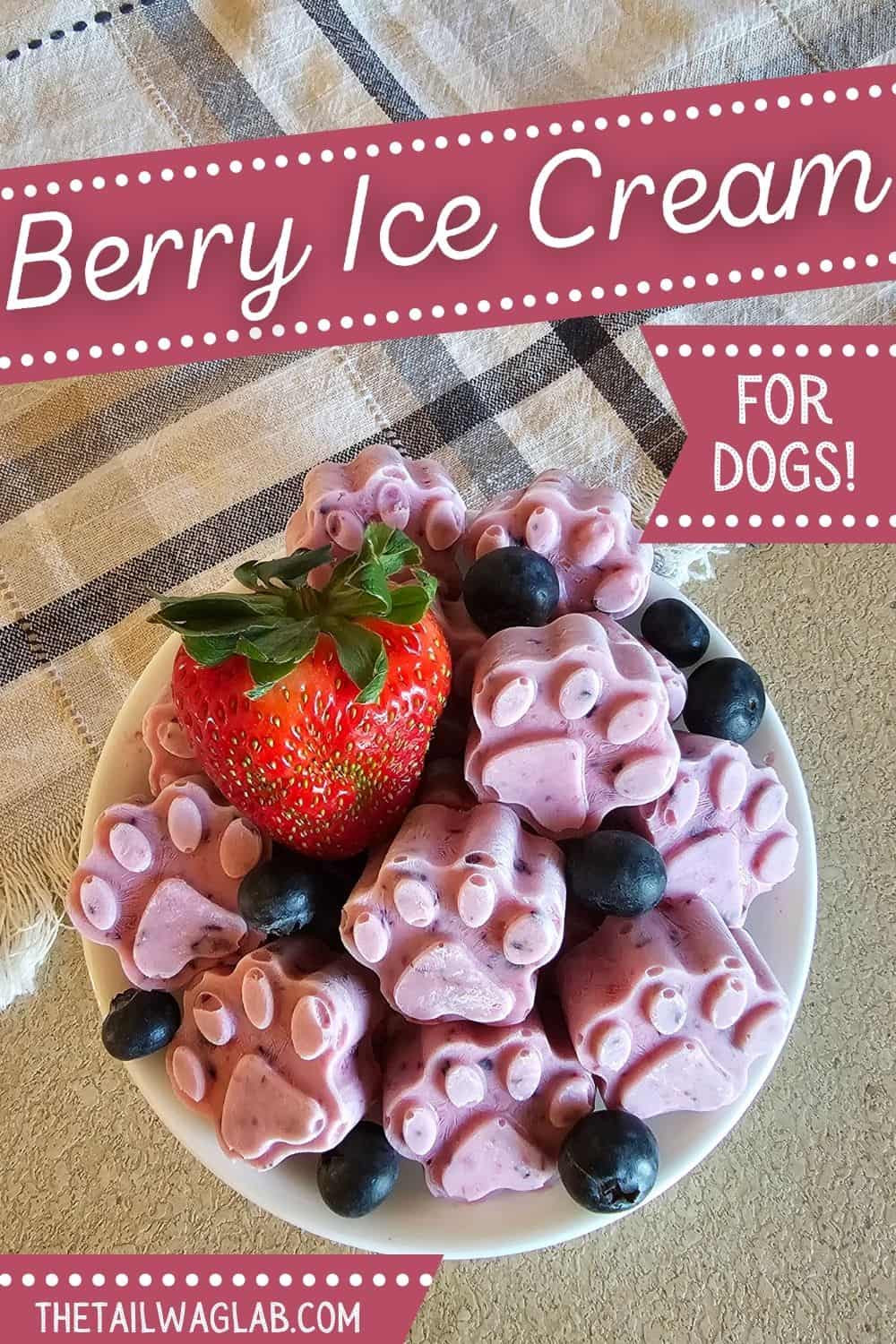 A bowl of homemade berry ice cream shaped like paw prints, topped with a strawberry and blueberries, presented on a patterned cloth.